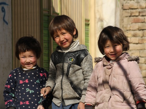Drie jonge kinderen kijken vriendelijk, foto genomen in Kabul, Afghanistan