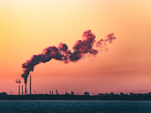 Iš naftos perdirbimo gamyklos kylantys dūmai, raudonų ir raudonų atspalvių dangus