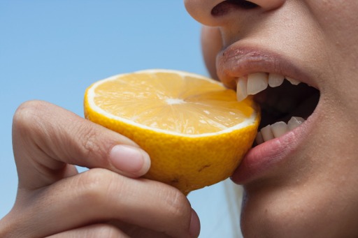face of woman biting in a lemon